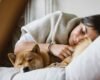 Sleep habits for adults: woman sleeping peacefully in bed with her dog