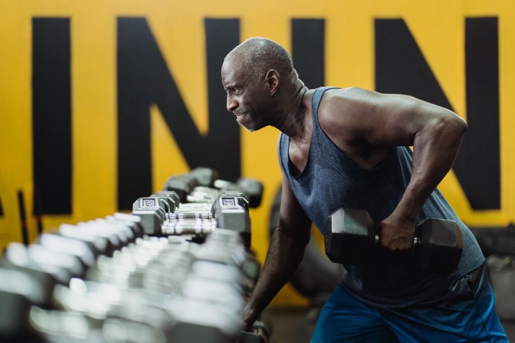 Strength training for older adults: senior man lifting dumbbells in a gym